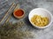 Fried noodles in a white bowl, with sauce in a small bamboo bowl