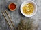 Fried noodles in a white bowl, with sauce in a small bamboo bowl