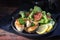 fried northern pike steaks with lemon, lettuce salad and tomatoes on a black plate, healthy low carb meal on a dark wooden