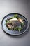 Fried Norwegian skrei cod fish filet with porcini mushroom and lettuce on a modern design plate