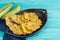 Fried patacones in black plate on blue wooden background. Copy space