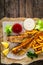 Fried perch with French fries and lemon served on paper on wooden table