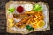 Fried perch with French fries and lemon served on paper on wooden table