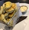 fried pickles in metal basket as an appetizer, a tie me over,