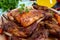 Fried pieces of rabbit with vegetables on a wooden tray on a dark background