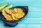 Fried plantain. Patacones on black plate on blue background. Copy space