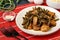 Fried pork with garlic arrows and soy sauce, sprinkled with sesame seeds in a plate, on a red mat, horizontal orientation