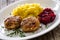 Fried pork meatballs with mashed potatoes and grated beets on wooden table