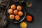 Fried potato cheese balls or croquettes with spices on black plate over dark stone background. Unhealthy food, top view