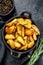 Fried potato wedges, French fries in a pan. Black background. Top view