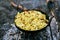 fried potatoes in a skillet cooked on a campfire in the forest, camping