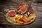 Fried ribs with rosemary, potatoes rustic, onion, sauce on wooden round Board.