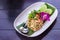 Fried rice with shrimp on the white ceramic dish decorated with orchid put on dark wooden table