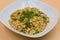 Fried rice with vegetables in white plate with peach background