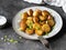 Fried roasted potato wedges with scallions on vintage plate on a dark gray background