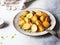 Fried roasted potato wedges with scallions on vintage plate on a gray background