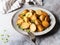 Fried roasted potato wedges with scallions on vintage plate on gray background