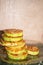 Fried ruddy courgettes are stacked in a column on a transparent patterned plate