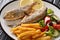 Fried Salema porgy fish with lemon and side dish of fresh vegetable salad close-up on a plate. horizontal