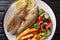 Fried Salema porgy fish with a side dish of fresh salad and french fries close-up on a plate. horizontal top view