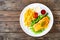 Fried salmon steak, French fries and fresh vegetable salad served on wooden table