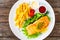 Fried salmon steak, French fries and fresh vegetable salad served on wooden table