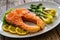 Fried salmon steak with lemon and steamed pak choi cabbage served on wooden table