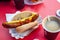 Fried sausage in a bun with mustard and ketchup with coffee in a cafe