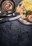 Fried sausage with potatoes and pickled cabbage served on dark rustic table background with cutlery