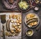 Fried sausages on baking tray served on plate with white coleslaw salad and mustard dip on rustic kitchen table, top view. German