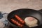 Fried sausages in a pan with scrambled eggs close-up and copy space. Boiled sausages and fried eggs breakfast in a frying pan