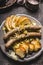 Fried sausages served with baked apples, onions and lye bun toast served on rustic table with white coleslaw salad, top view, clos