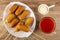 Fried sausages on skewers in dish, sauce boat with mayonnaise, cup with tomato juice on table. Top view