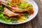 Fried sea bass with fried potatoes and fresh cabbage salad on wooden table