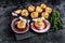 Fried seafood scallops meat with butter in a shells. Black background. Top view