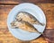 Fried short-bodied mackerel on blue plate with wooden background
