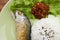 Fried Short-bodied mackerel with rice on green plate.