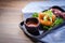 Fried shrimp in panko on a black plate on wooden table background. Crispy mayo panko prawn rolls with salad garnish