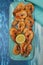 Fried shrimps or prawns with lemon on a blue plate on a blue background. Banner, menu, poster. Copy space. Vertical photo.