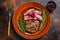 Fried sliced flank or bavette beef meat steak on a plate. Dark background. Top view