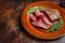 Fried sliced flank or bavette beef meat steak on a plate. Dark background. Top view. Copy space