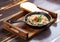 Fried snails in cream sauce, in a cast iron pan. On a wooden stand