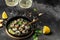 Fried snails Escargots de Bourgogne with herbs, butter, garlic on metal plate with forks, wine glass. gourmet food. Restaurant