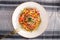 Fried soba noodles with mushrooms, carrots, peppers closeup on white plate on fabric background