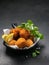 Fried Spanish bacalao croquettes in iron pan made with breaded salted codfish and served as traditional tapas or snacks. Dark