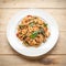 Fried spicy Thai-style seafood spaghetti on a white plate, on a wooden background