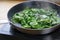 Fried spinach leaves in a pan on the stove, healthy cooking concept