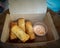 Fried spring rolls in a brown takeaway container with creamy sauce