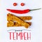 Fried tempeh decorated with chilly smile. YUMMY TEMPEH caption. Top view.