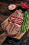 Fried Top Blade or flat iron roast beef meat steaks on wooden board with rosemary. Dark wooden background. Top View